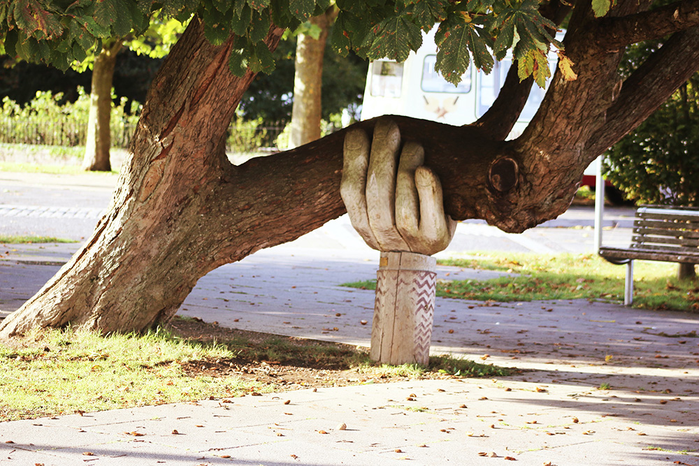 Skulptur i form av en hand stöder ett träd