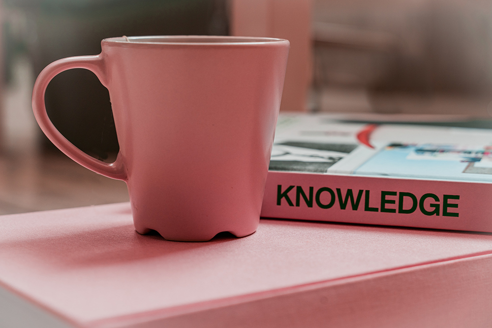 Rosa kopp och boken om "knowledge" på rosa bord