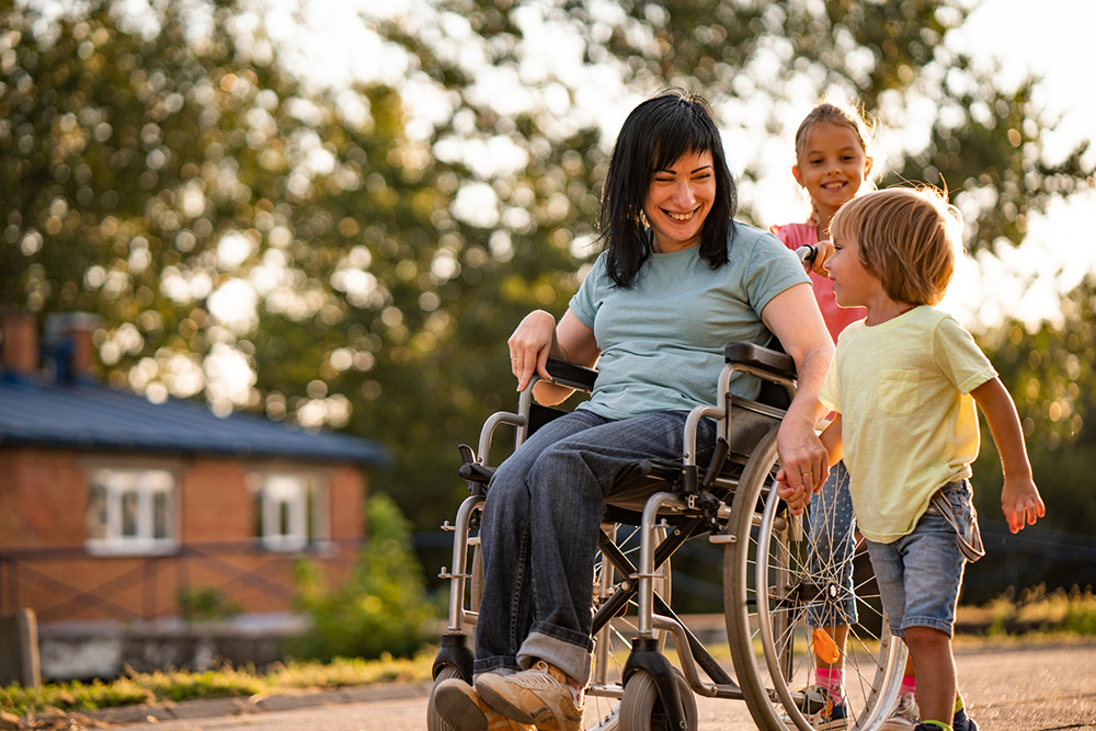 Kvinna i rullstol på promenad med två barn