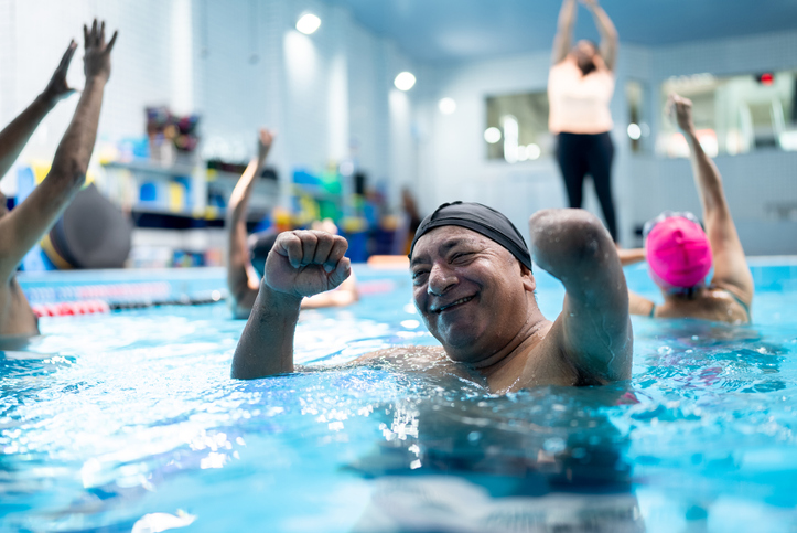 Portrait of a senior man with left arm amputation during a group fitness class at swimming pool