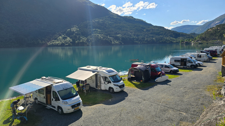 Scenic camping along Fjord in Norway with motorhomes and kayaks surrounded by mountains